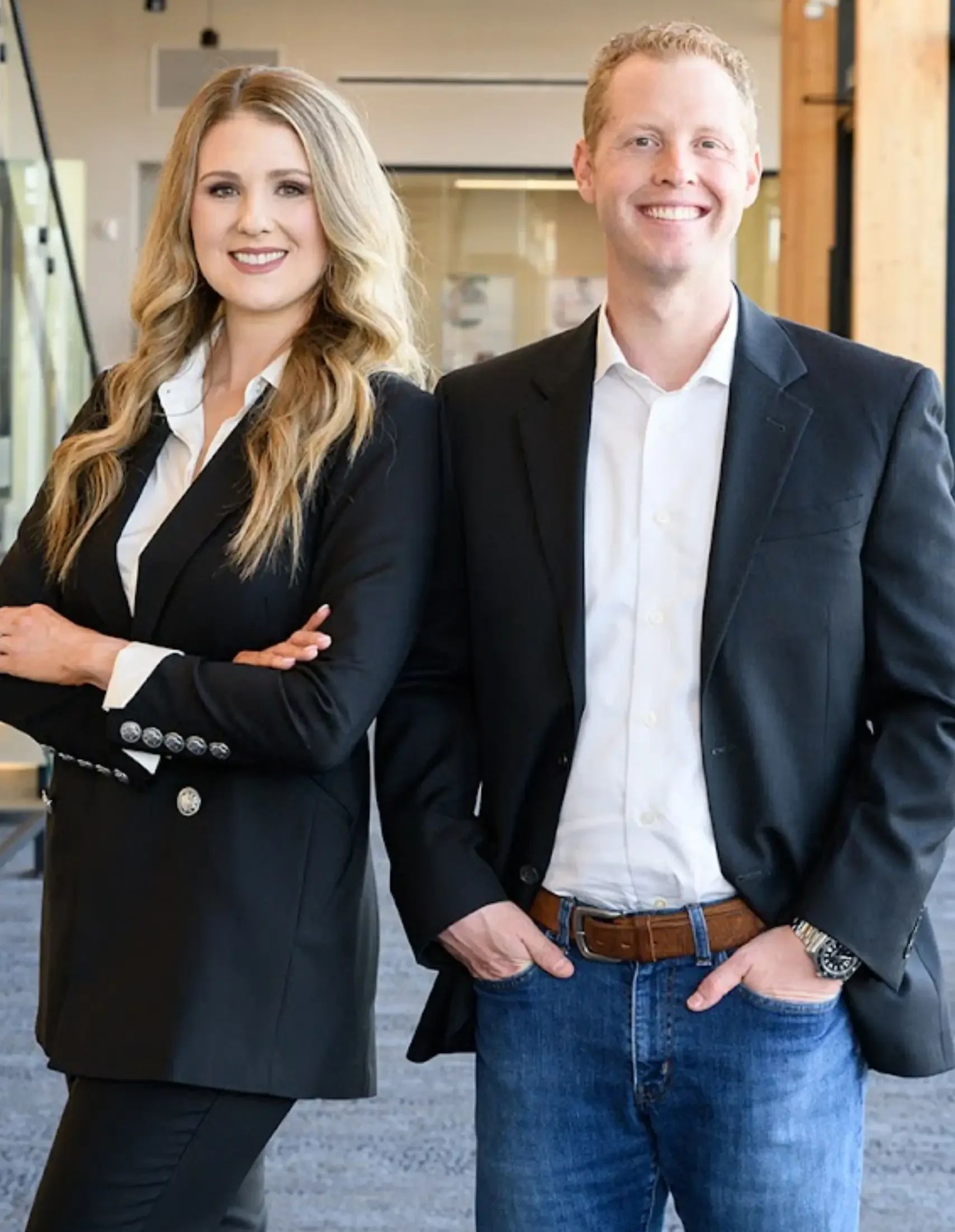 Two professionals in smart attire posing for a photo indoors.